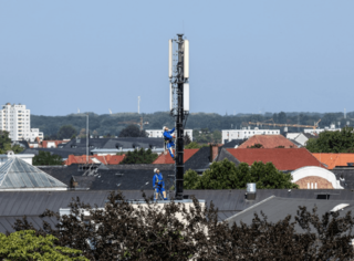 Techniker der Deutschen Funkturm warten eine Mobilfunkantenne auf einem Hausdach